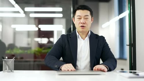 Happy asian businessman finished work on computer while sitting at workplace in business office.