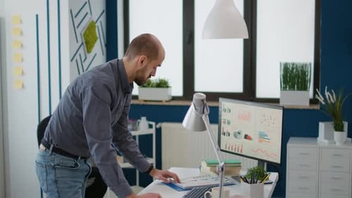 Man Reviews Charts and Graphs at Office Desk