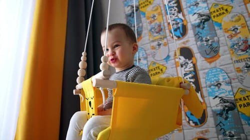 Adorable Child Enjoying a Fabric Swing Indoors