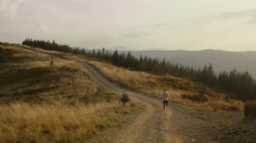 Wide Active Athlete Jogging in Mountain Landscape. Young Guy Running On