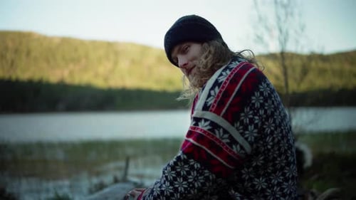 Man in Beanie Sits Contemplatively near Lake