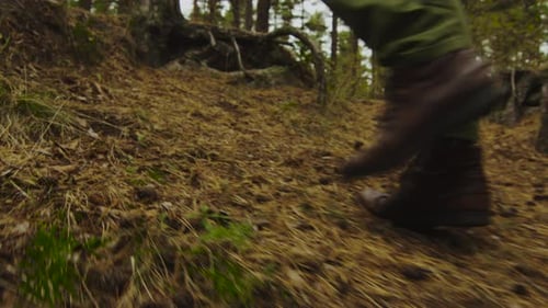 Hiker in close-up slow motion leg shot walks uphill in the forest in autumn.