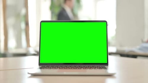 Laptop with Green Screen on Desk in Office