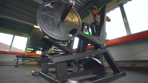 wide low angle shot of a man using a modern weight lifting machine at the gym to train his upper bod