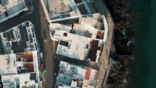 Aerial view of urban architecture and coastline at sunset, Spain.