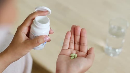 Woman Pours Pills into Hand with Water