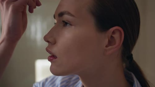 Young Woman Applies Makeup with Brush Indoors