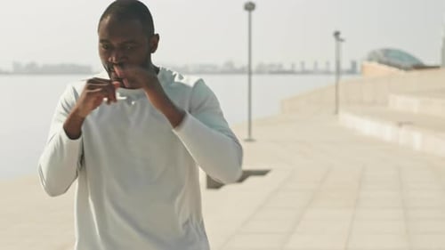 Man Practices Boxing on Sunny City Waterfront