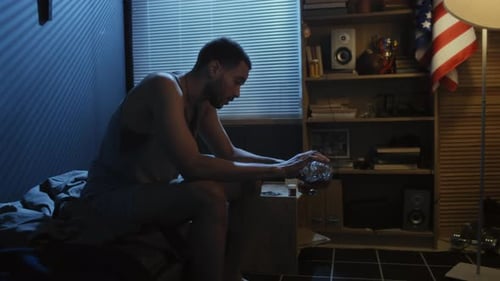 Sad Young Man Drinking Alone in Bedroom at Night