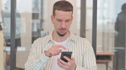 Porträt eines kreativen jungen Mannes mit Telefon