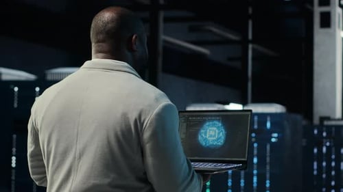 IT Expert Walking in Server Hub Using Laptop to Enhance AI Model Accuracy
