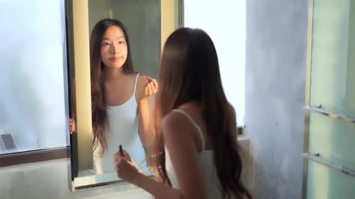 Beautiful Asian Woman Puts on Lipstick in Front of Bathroom Mirror, Slow Motion Full Frame