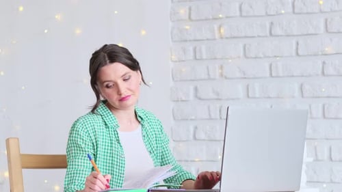 Woman Sitting at a Table Working at a Laptop Computer Concept of Remote Work From Home Home Office