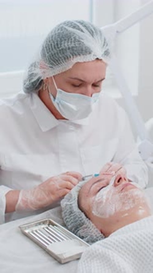 Kosmetikerin macht junge Frau Schönheit Anti-Aging-Injektionen Biorevitalisierung Gesichtsmesotherapie