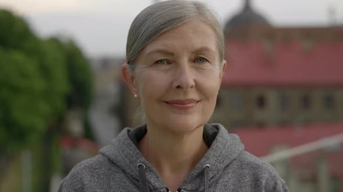 Portrait of the Beautiful Smiled Eldery Woman Looking at the Camera Standing Outside Before the