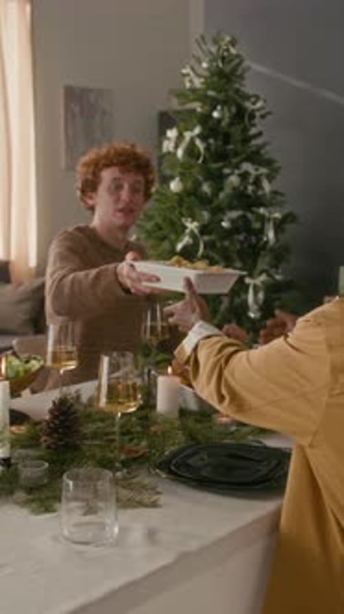 Vertical of Positive Young Man Handing Dish to Friend Celebrating Christmas