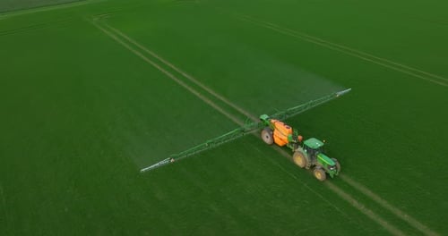 Aerial View of Farming Tractor Spraying on Field with Sprayer Herbicides and Pesticides at Sunset