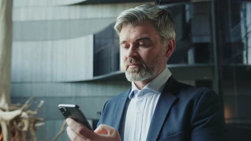 Businessman in Suit Using Smartphone Inside Building
