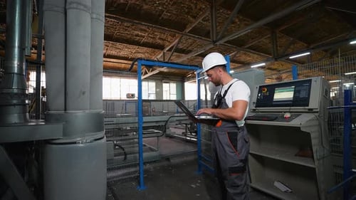 Der Programmierer für Industriearbeiter richtet den Förderband der Produktionslinie mit Laptop ein