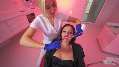 Blonde female dentist pulling out vampire teeth.