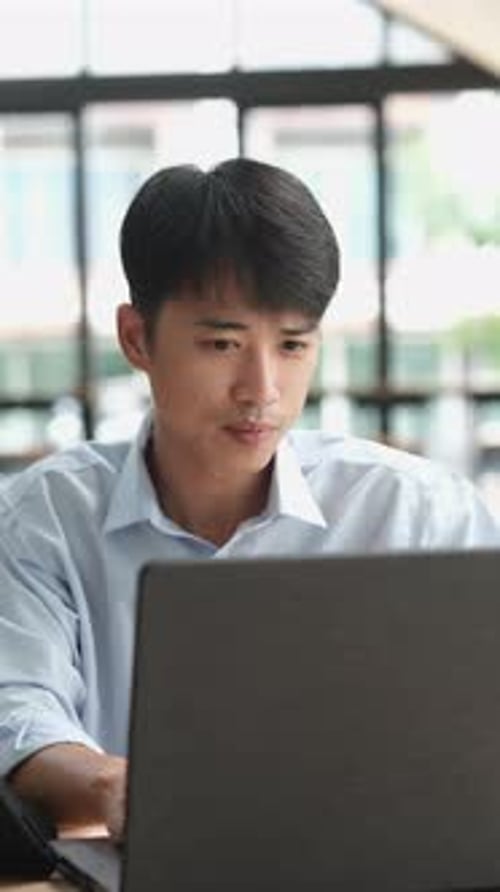 Young Adult Working at Laptop at Desk Indoors