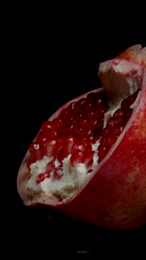 Vertical video. Half of a Split Pomegranate with Red Seeds, isolated, looped video.