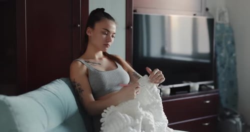 Young Woman Knitting a Blanket on the Sofa