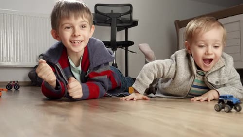 Two Children Play with Toy Cars on Wood Floor