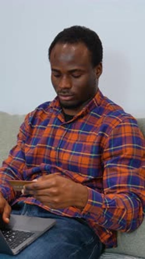 Young Adult Using Laptop and Credit Card at Home