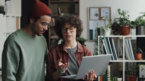 Colleagues Discussing Online Presentation on Laptop