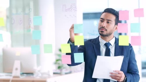 Business man thinking of ideas, planning a strategy and writing notes on a glass wall in an office