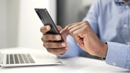 Close up of male hands holding mobile phone. African american businessman is using smartphone while