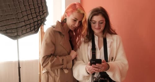 Female Photographer and Model is Looking for Ideas for a Photo Shoot on Her Smartphone in the Studio