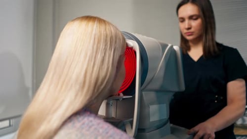 Close Up in an Ophthalmology Clinic Female Doctor Performs Diagnostics Using a Device with Red