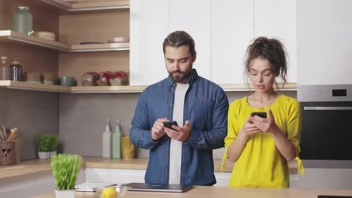 Couple Uses Phones, Smiles at Each Other