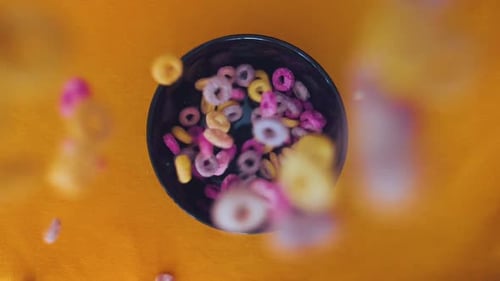 Colorful Cereals falling in a bowl in slomotion topview.