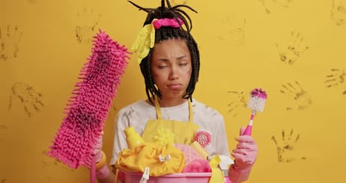 Overwhelmed woman with cleaning supplies and dirty face