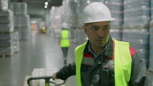 Worker Pulling Cart with Pallet at Warehouse