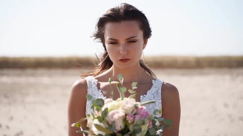 Elegant Woman with Bouquet on a Sunny Beach
