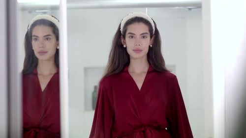 Elegant Woman in Robe Looks at Herself in Mirror
