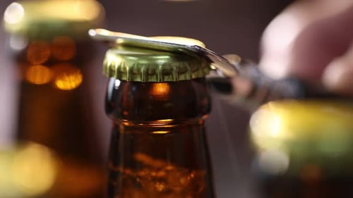 Opening beer bottle with opener in close up
