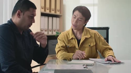 Man Showing Business Paper with Chart while Talking to Co-worker at Office