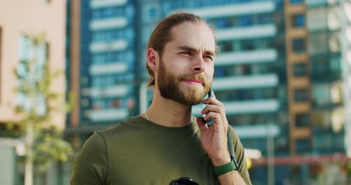 Close Up of Young Happy Caucasian Handsome Man Standing Outside Sipping Coffee and Speaking on