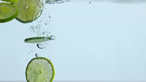 Lime Slices Falling Into Water, Bubbles Forming