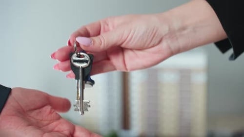 Real Estate Handover with Close Up of Key Passed to New Property Owner