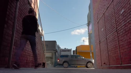 Urban alley way street opening, looking onto suburban activity as car's and pedestrians pass by.