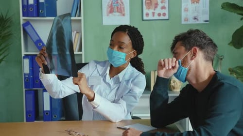 Doctor Reviews X-Ray with Concerned Male Patient