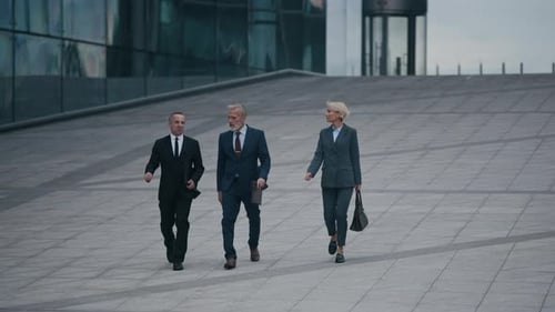 Entrepreneurs Walking towards Camera on Square with Glass Office Buildings