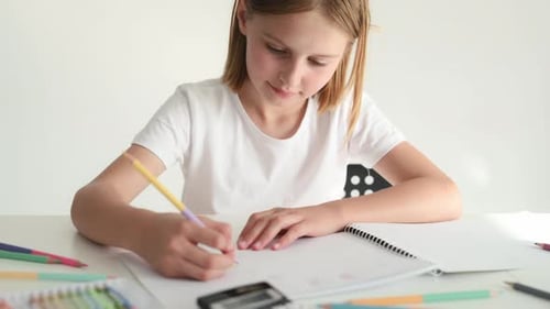 Girl Draws with Colored Pencils at a Table
