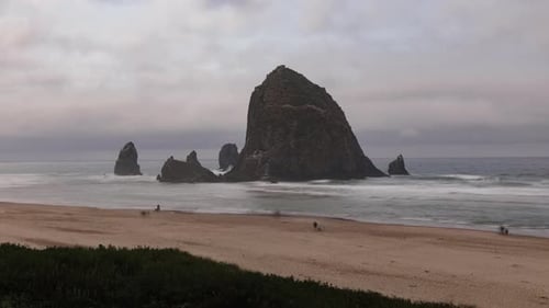Wide shot of Cannon Beach and the famous Haystack Rock with people on the beach